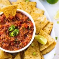 Top down shot of salsa in a white ramekin with chips around it.