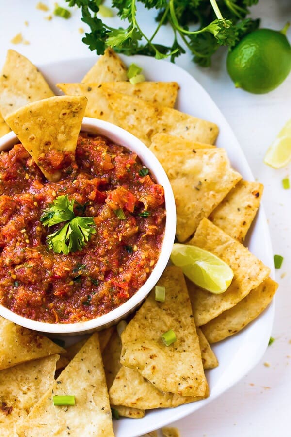 Top down shot of salsa in a white ramekin with chips around it.