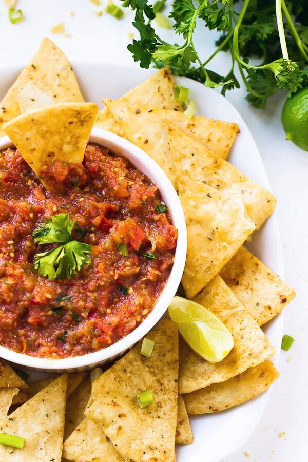 Top down shot of blender salsa in a white bowl with tortilla chips on the side. 