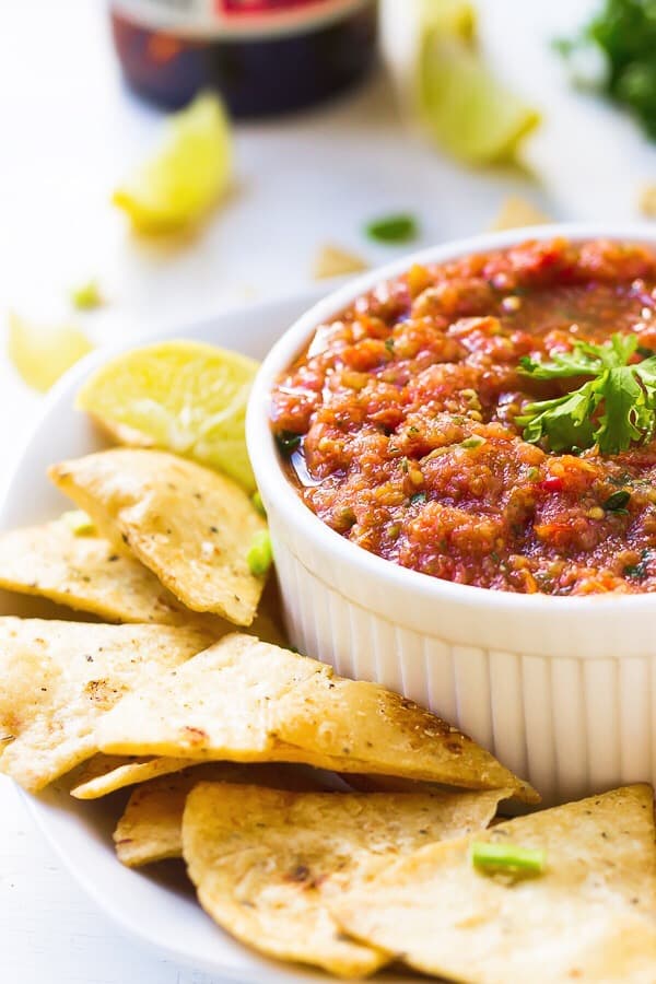Restaurant style blender salsa in a white ramekin surrounded by chips. 