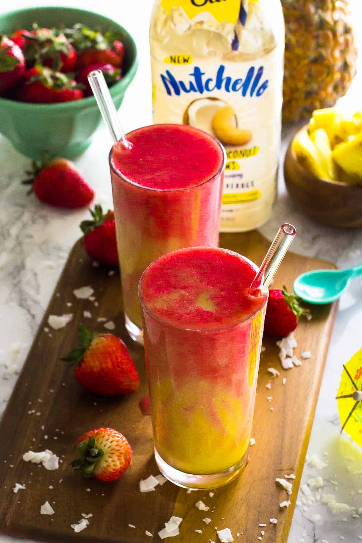 Tow tall glasses of strawberry pineapple coconut smoothies.
