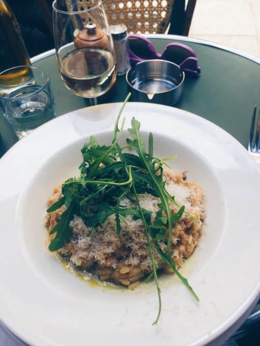 A white dish with arugula on a restaurant table. 