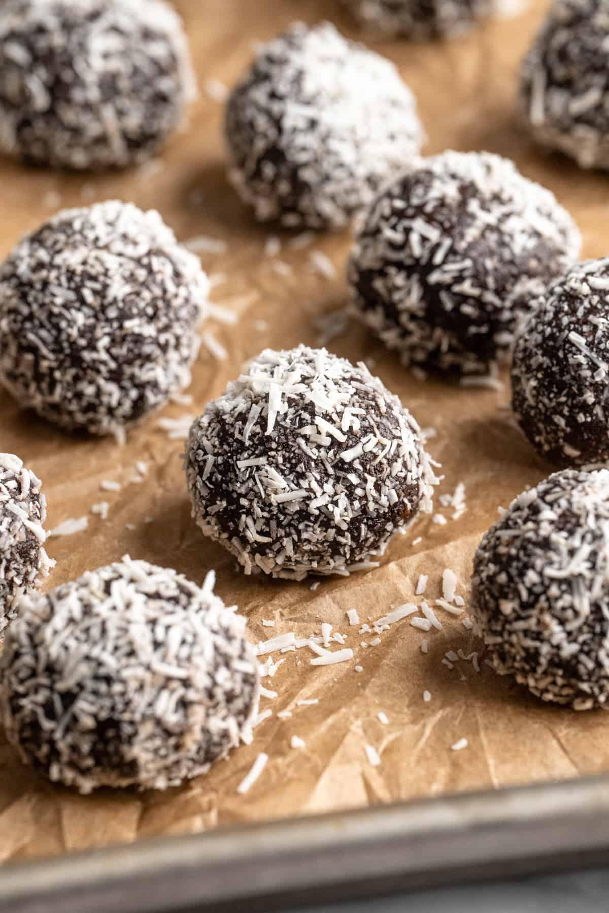 Vegan no bake brownie energy bites on parchment lined pan.