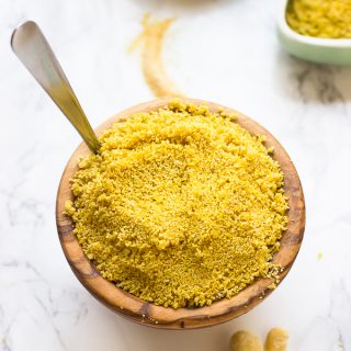 Small wooden bowl of vegan parmesan cheese with spoon