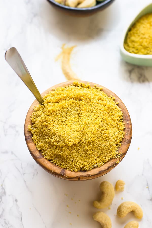 Small wooden bowl of vegan parmesan cheese with spoon