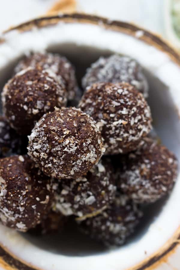 Close up of No bake brownie energy bites in a pile inside of a half of a dried coconut shell.