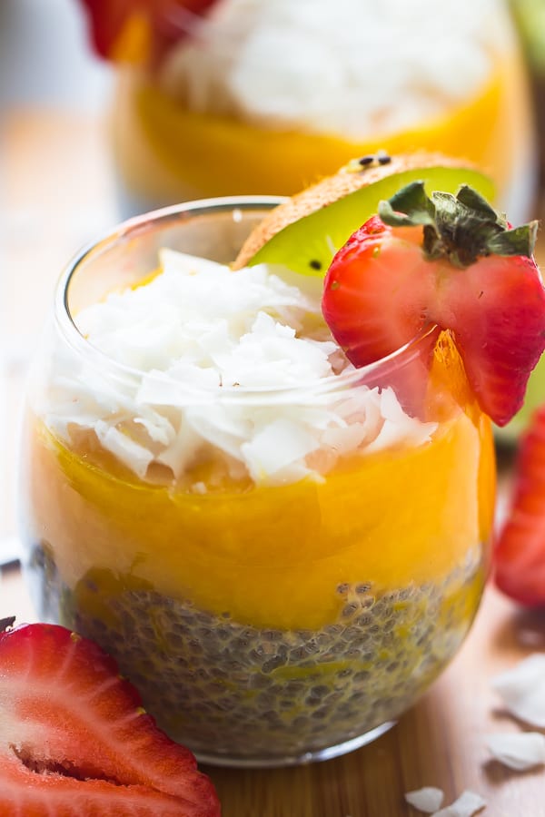 Close up of mango coconut chia seed pudding in a wine glass, with another pudding in the background.