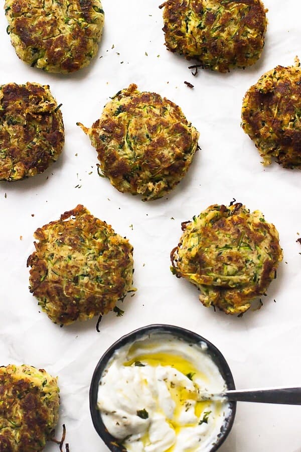 Overhead view of gluten-free vegan zucchini fritters and bowl of sauce