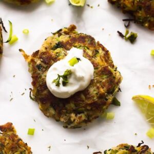 A vegan zucchini fritter with sauce on top.