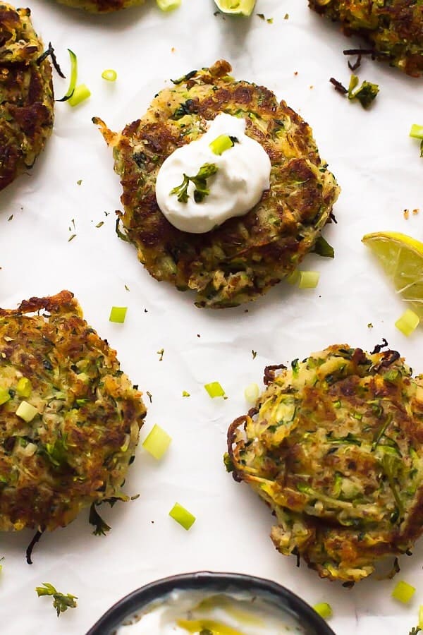 Closeup of vegan zucchini fritters, one with dollop of sauce on top