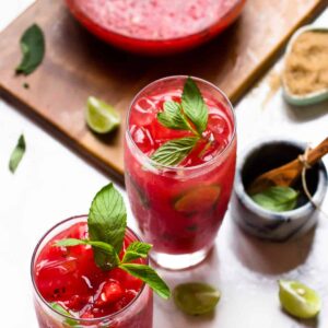 Two watermelon mojitos with pitcher on wood board