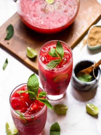 Two watermelon mojitos with pitcher on wood board