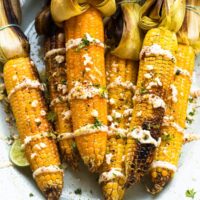 Top down shot of grilled corn on a white plate.