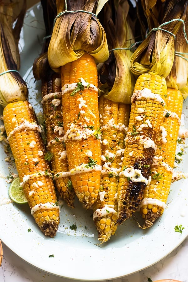 Top down shot of grilled mexican street corn on a white dish.