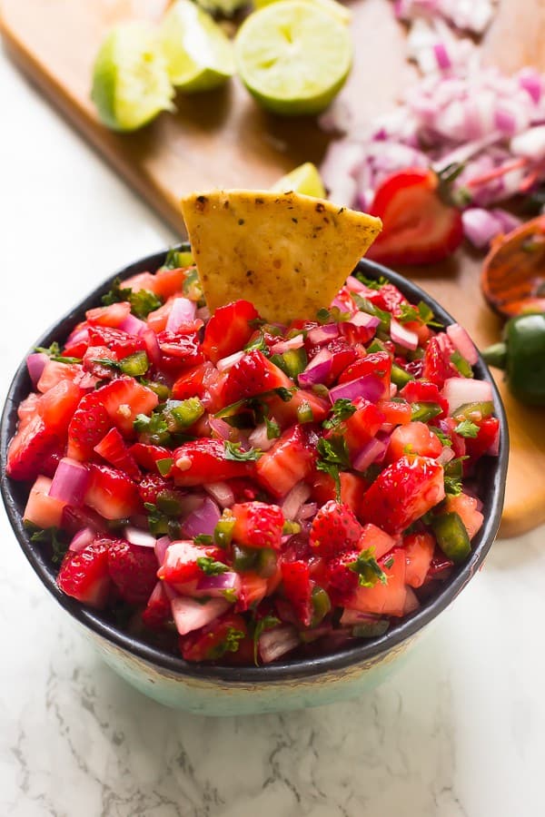 Top down shot of strawberry jalapeno salsa with a tortilla chip dipped in. 