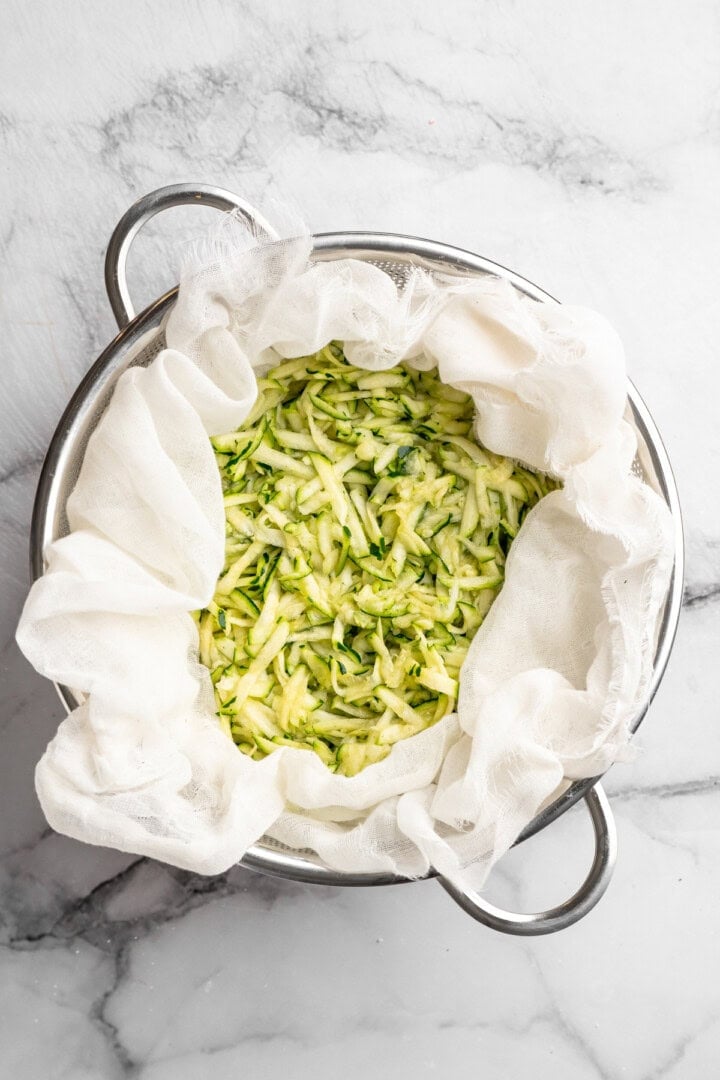 Shredded zucchini draining in colander. - 3