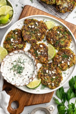 Platter of zucchini fritters with vegan feta, tzatziki, and fresh dill.