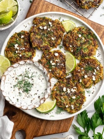 Platter of zucchini fritters with vegan feta, tzatziki, and fresh dill.