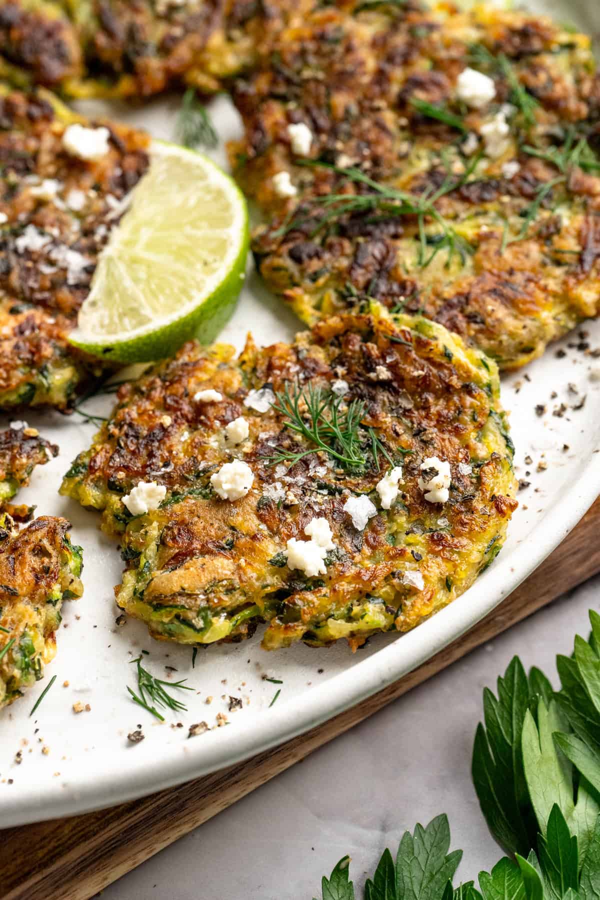 Crispy vegan fritters on platter topped with vegan feta and dill. - 6