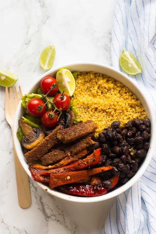 Top down shot of a fajita bowl with a wooden spoon on the side. 