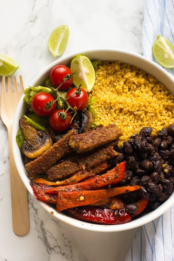 Overhead shot of a vegan fajita bowl with lime wedges and a fork on the side. 