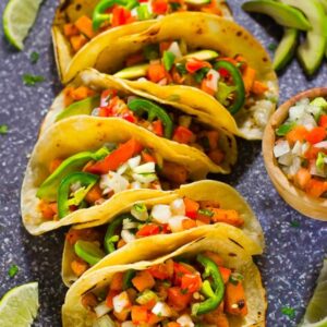 Top down shot of vegan tacos with wedges of lime.