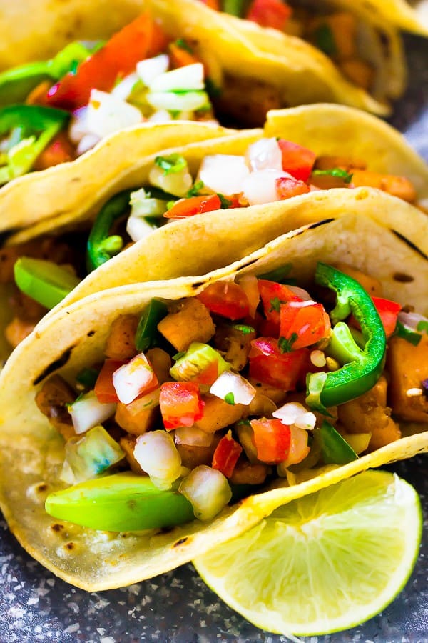 Close up of vegan sweet potato tacos with a wedge of lime. 