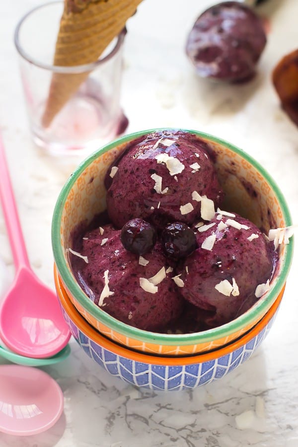 Three scoops of blueberry banana ice cream in a colorful bowl.