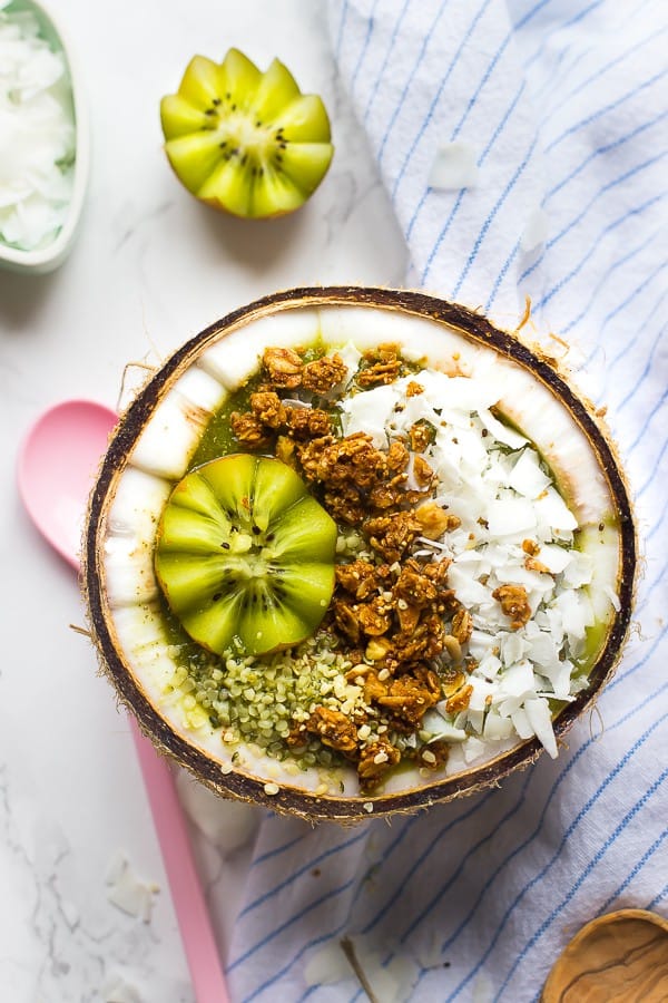 Top down shot of coconut kiwi green smoothie bowl in a coconut.