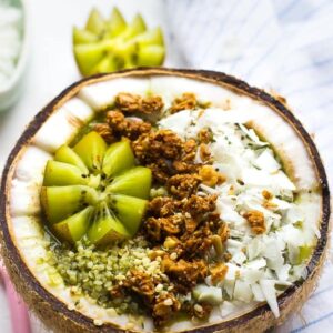 A coconut kiwi green smoothie bowl in half a coconut.