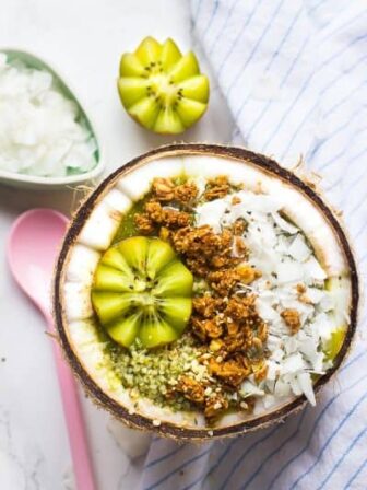 Top down view of a coconut kiwi green smoothie bowl in a coconut.