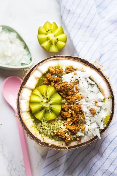 Top down view of smoothie bowl in a coconut with a spoon on the side. 