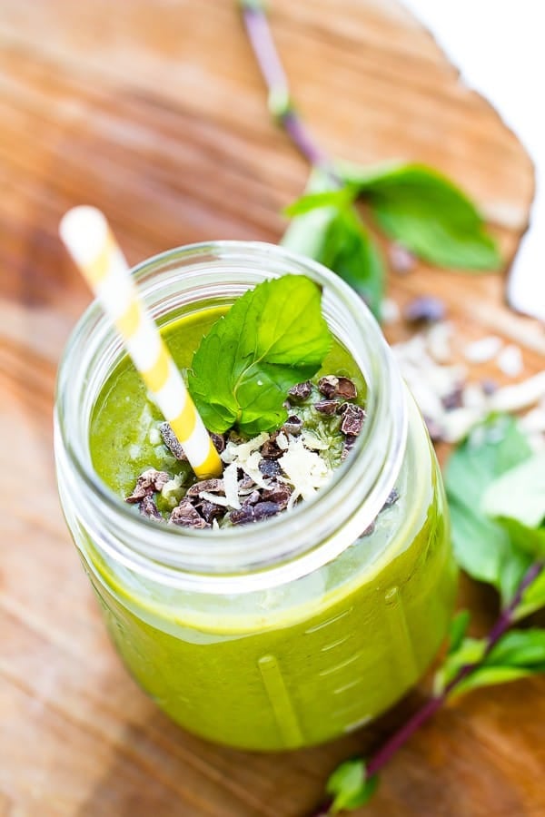Top down shot of mint chocolate chip green smoothie in a mason jar with a yellow straw. 