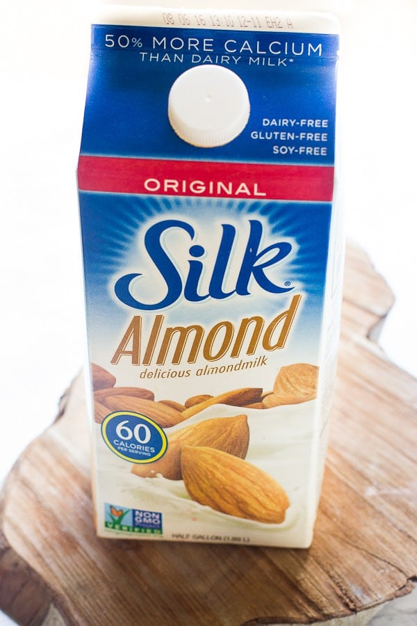 A carton of almond milk on a wood table. 