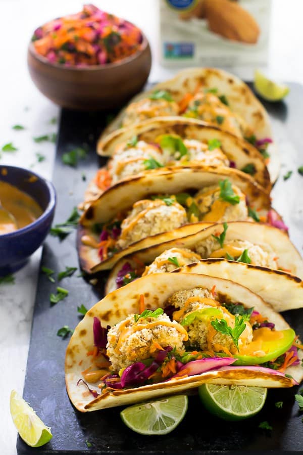 A row of cauliflower tacos with slaw in the background. 
