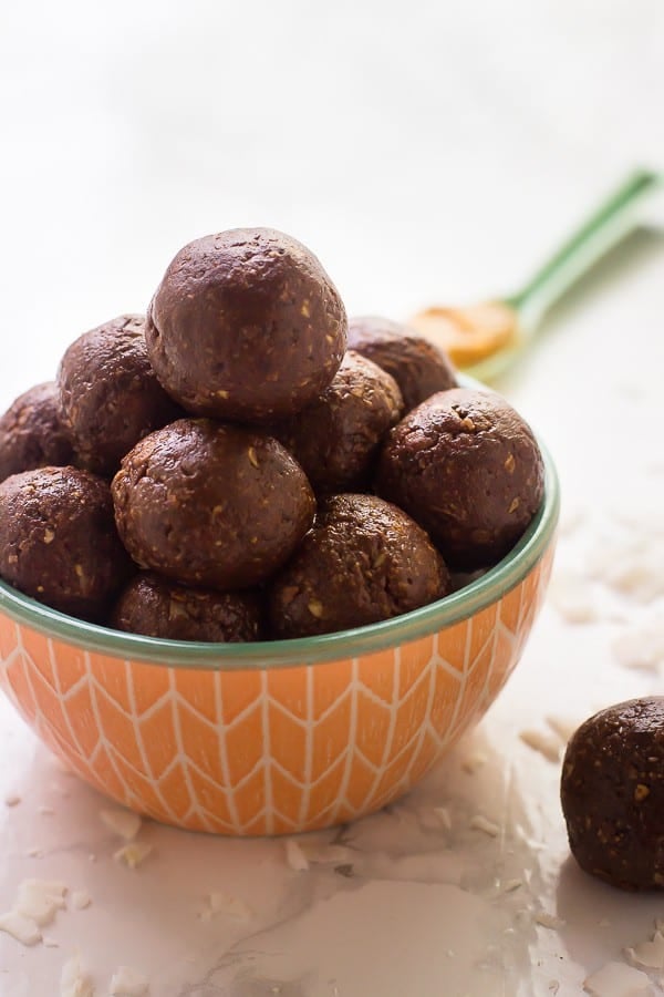 Side shot of chocolate peanut butter energy bites in an orange bowl. 