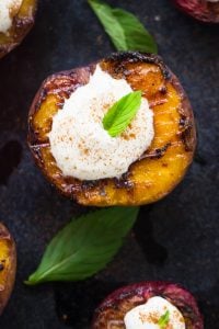 Top down shot of grilled fruit topped with coconut cream on a grey slate.