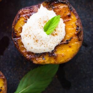 Top down shot of grilled fruit topped with coconut cream on a grey slate.