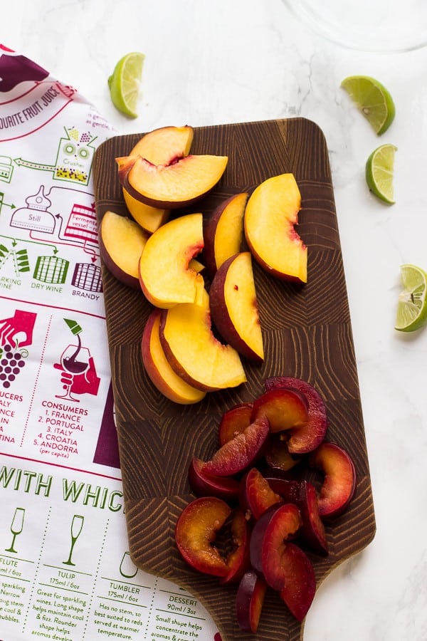 Top down shot of stone fruit slices on a wood chopping board.