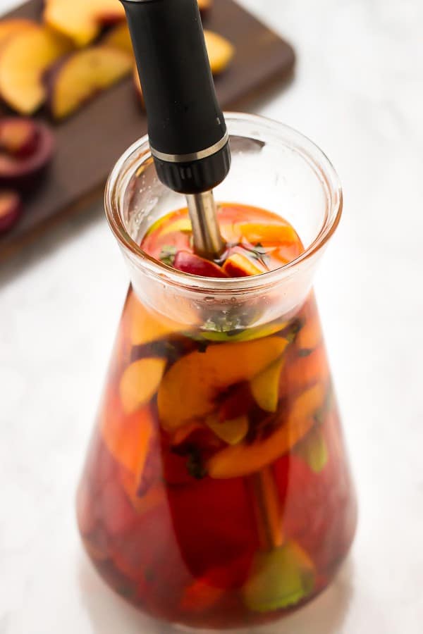 Stone fruit sangria in a pitcher on a white table. 