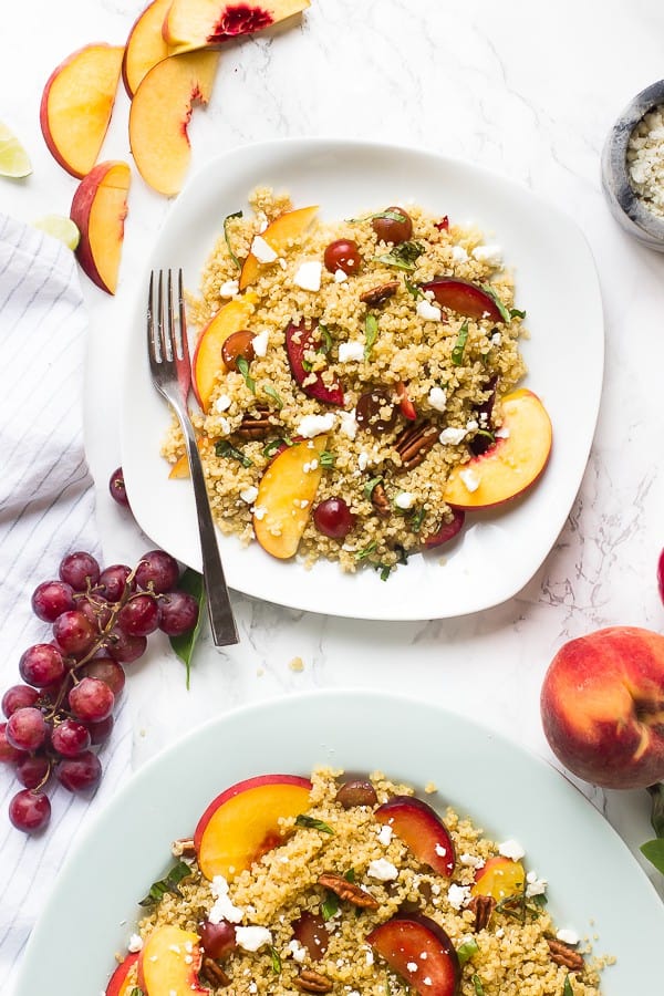 To down shot of quinoa stone fruit salad on a square plate with slices of peach on the side.