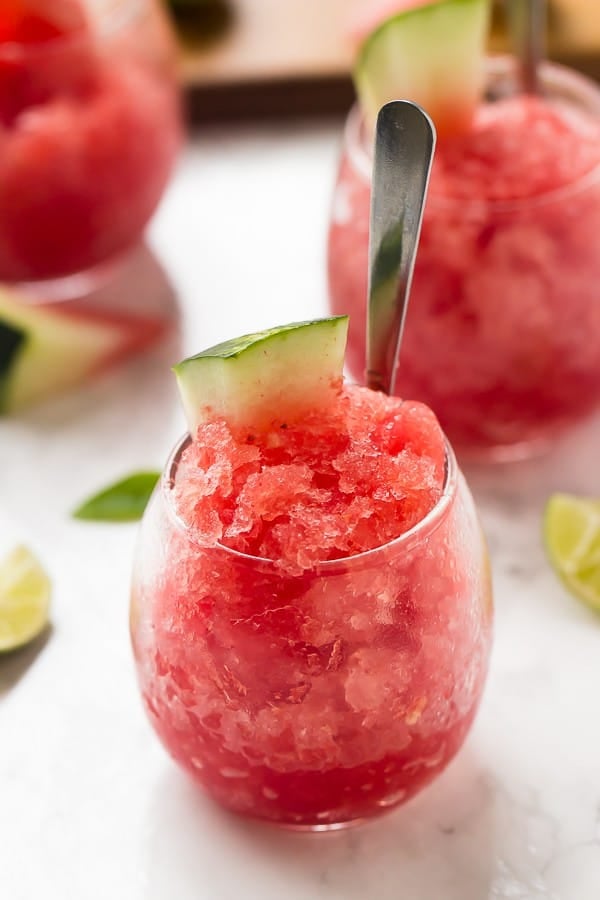A round glass full of watermelon granita, topped with a slice of watermelon. 