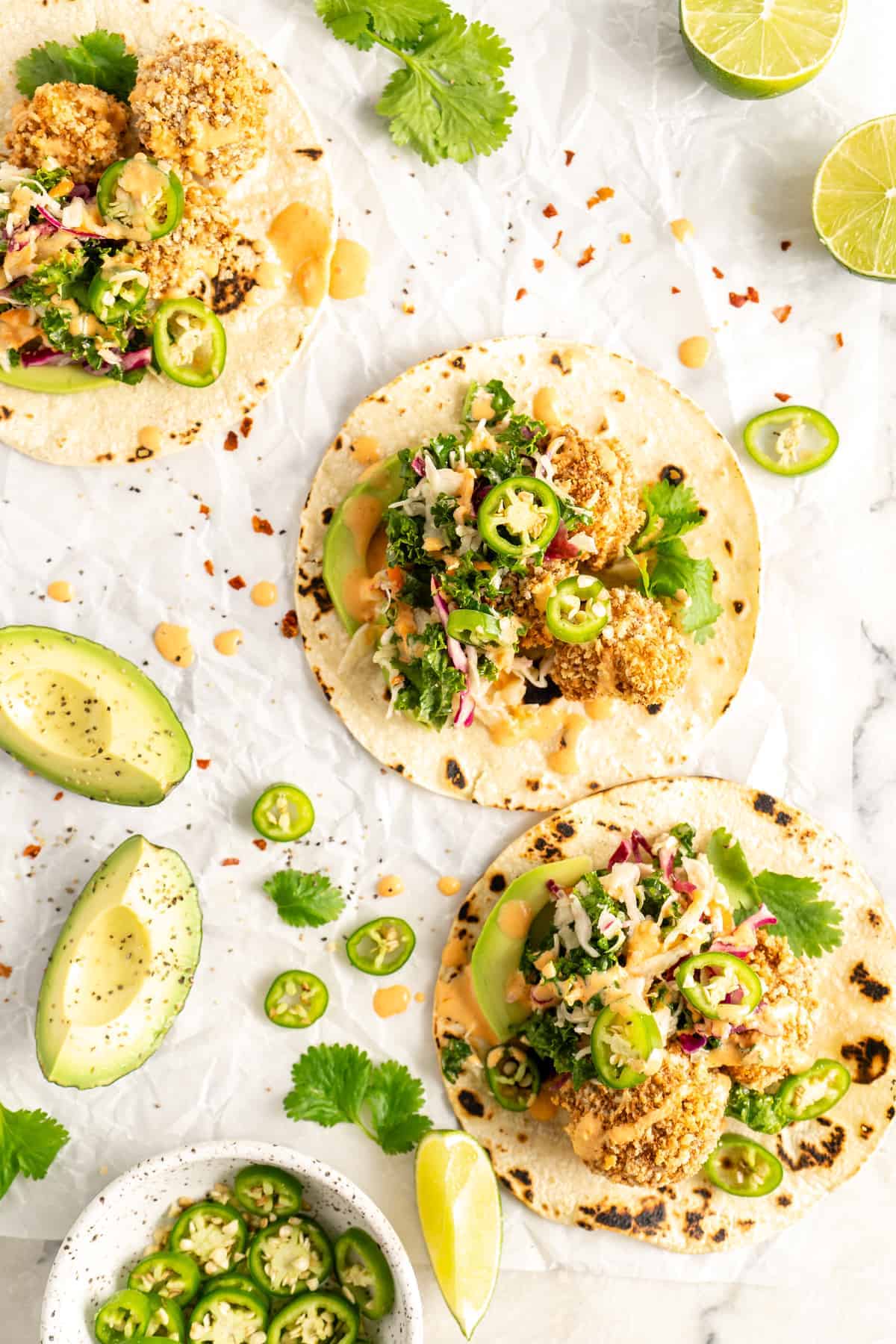 Overhead view of assembled Crispy Cauliflower Tacos surrounded by garnishes