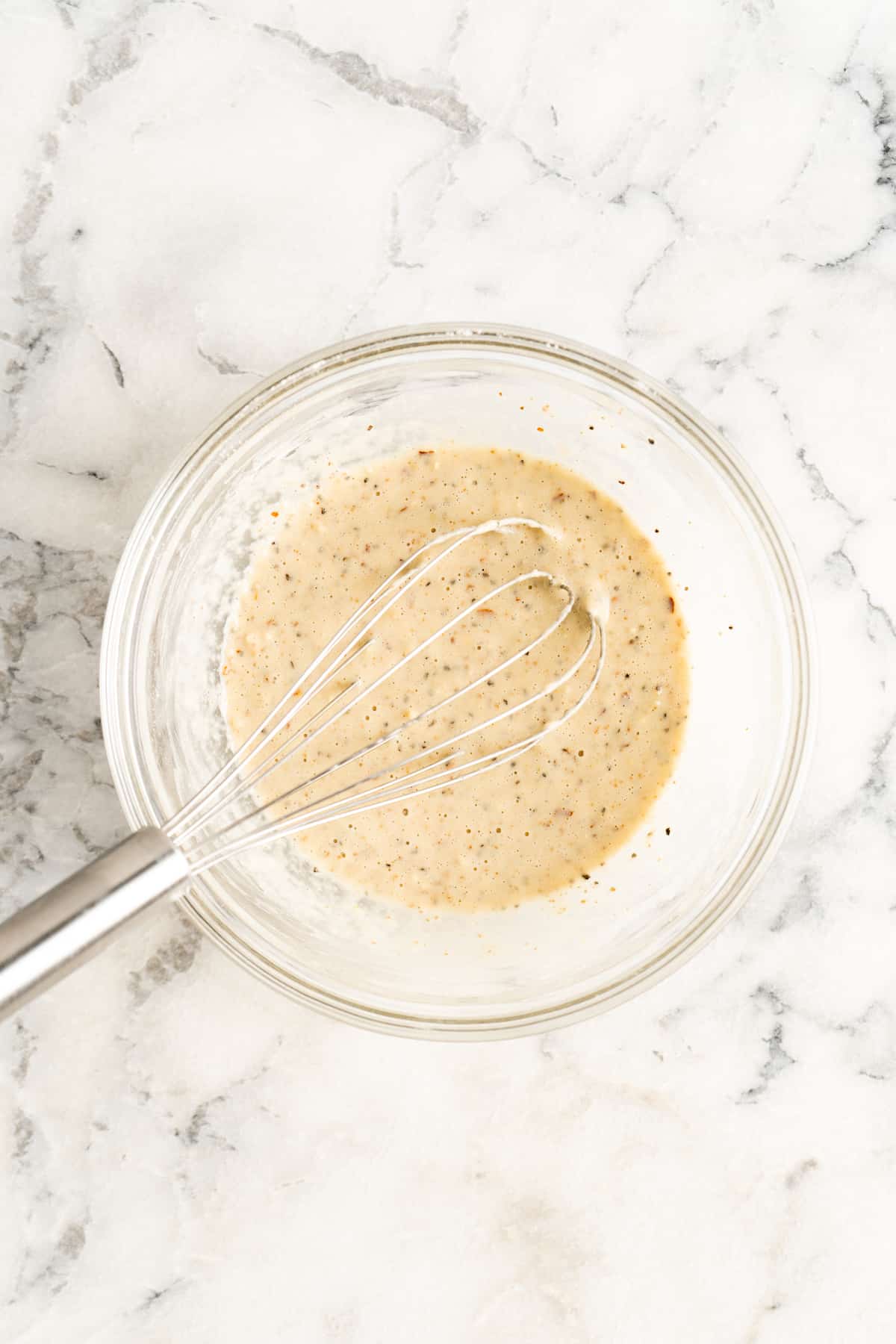 Overhead view of batter in glass bowl with whisk