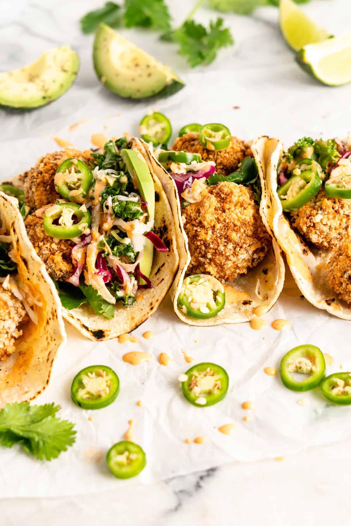 Side view of tacos filled with crispy breaded cauliflower, slaw, and sliced jalapenos