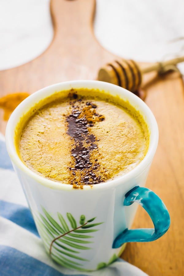 Close up of pumpkin Spice Golden Milk in a mug on a wooden board. 