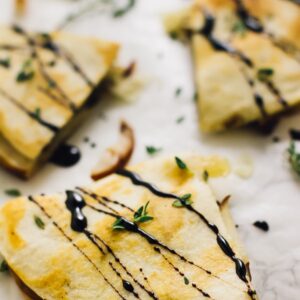 Overhead shot of pear brie & caramelised onions quesadillas on parchment paper.