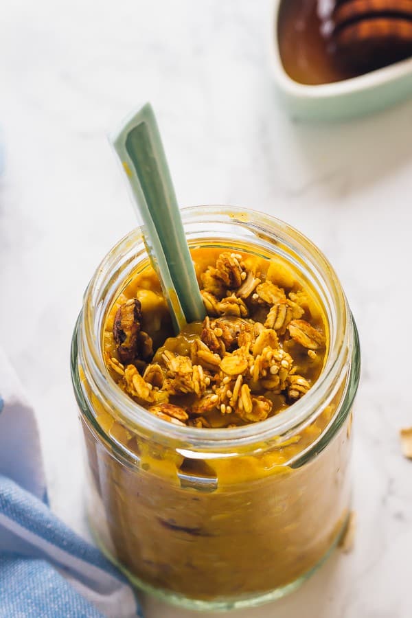 Overhead shot of pumpkin pie overnight oats in a glass jar with a spoon.