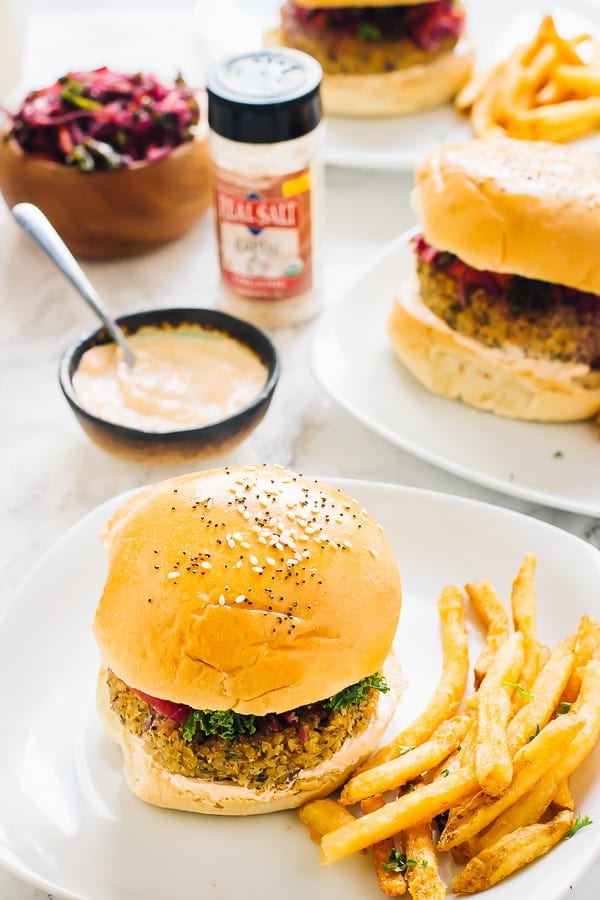 Two vegan quinoa cauliflower burgers on a white plates with fries on the side. 