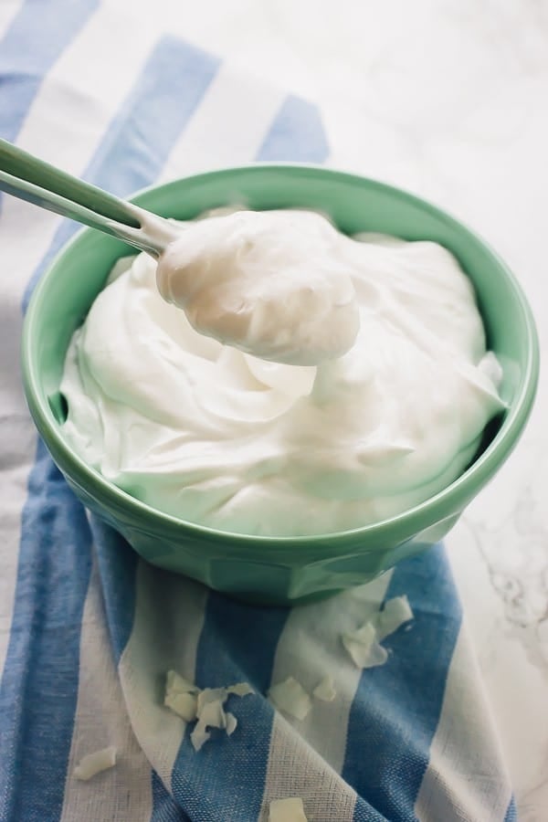 A spoonful of coconut whipped cream in a green bowl. 
